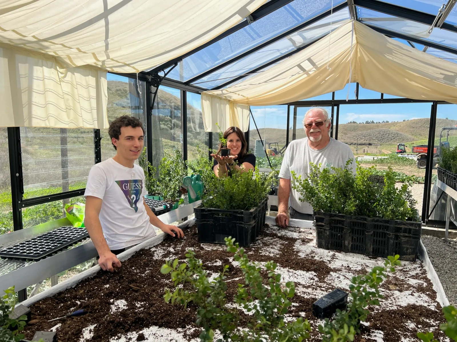 Ben with a farm family working around young plants in a greenhouse