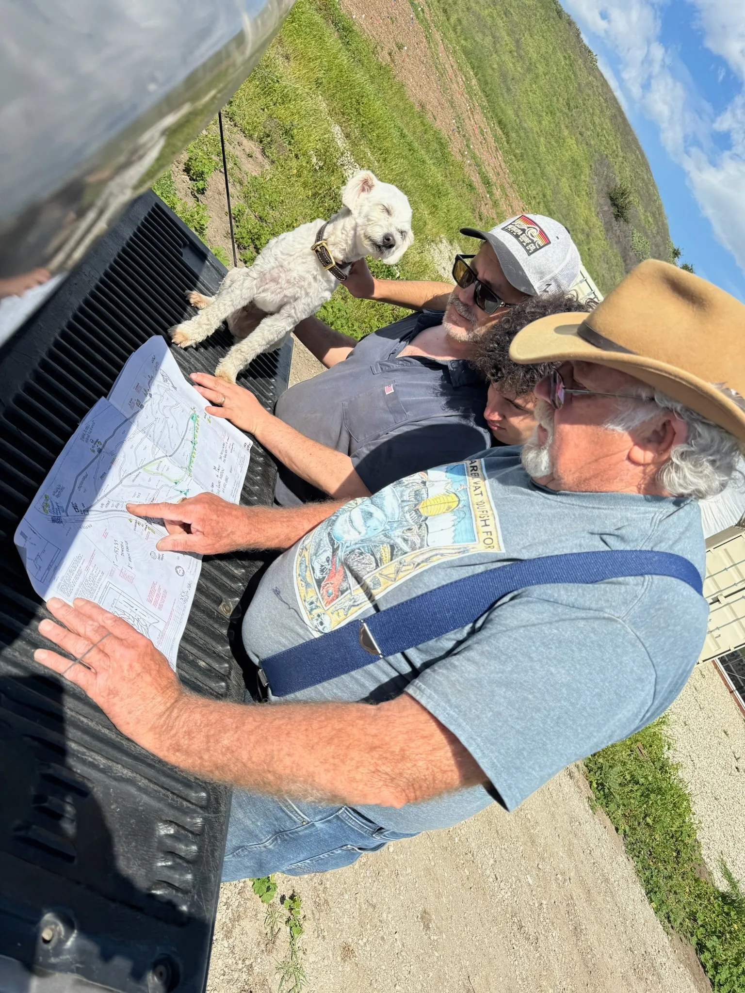 Ben and a farm family reviewing site plans on the bed of a pickup truck